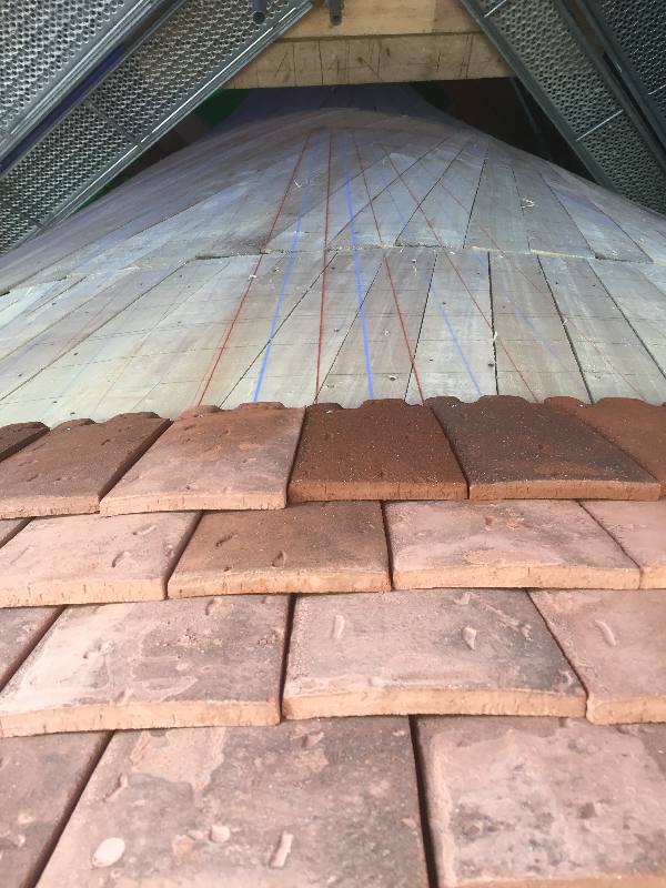 Tuiles taillées en largeur et alignées sur les ournes bleues et rouges